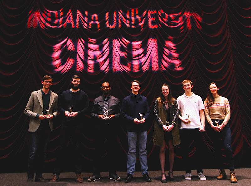 Seven students smile in front of an IU Cinema backdrop after winning awards at Montage Film Festival.